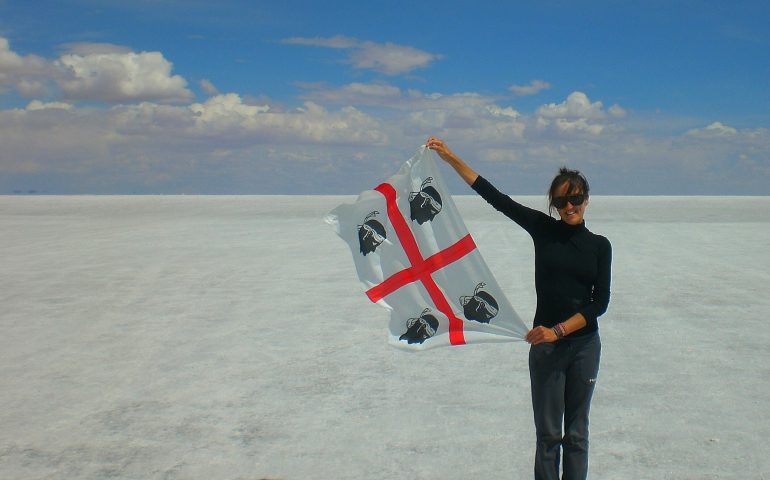 La foto ritrae Claudia Tavani, blogger, durante uno dei suoi viaggi, mentre mostra la bandiera dei quattro mori