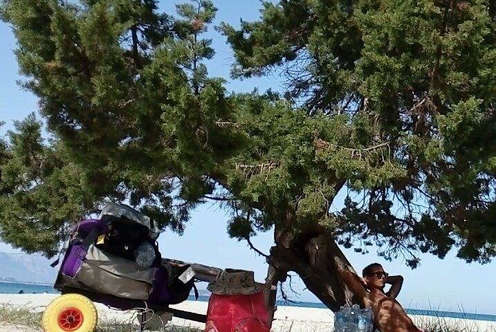 Un ragazzo si rilassa in spiaggia all'ombra di un albero