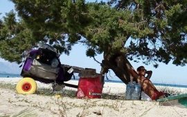 Un ragazzo si rilassa in spiaggia all'ombra di un albero