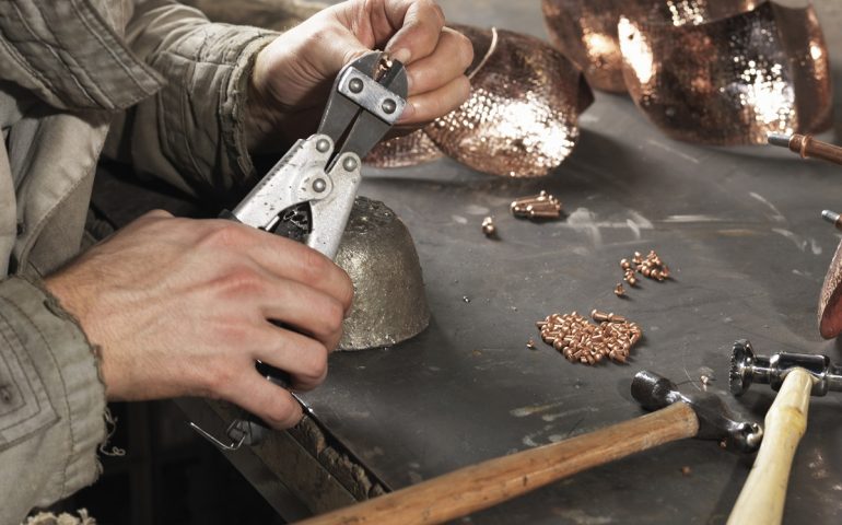 Cropped image of blacksmiths hands working with copper rivets