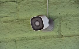 A home security camera is mounted on an outside wall.