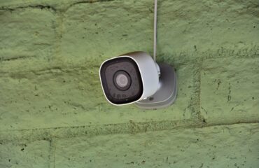 A home security camera is mounted on an outside wall.