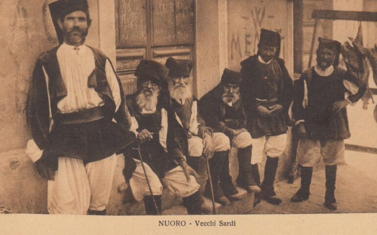 Vecchia cartolina con uomini sardi in costume a Nuoro