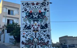 Un enorme arazzo sardo campeggia su un murale in un’isoletta sarda: dove ci troviamo?