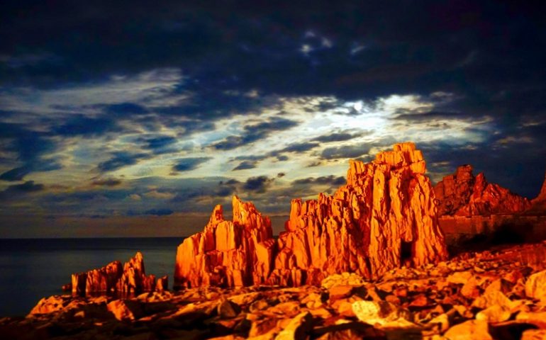 Le foto dei lettori. Meraviglia alle Rocce Rosse, una luce nella notte le avvolge: scatto di Luigi Pani