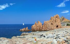 Una vela bianca, il blu del mare e le Rocce Rosse: uno scorcio suggestivo che racconta la bellezza di Arbatax