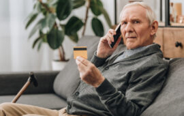 senior man talking on smartphone and holding credit card