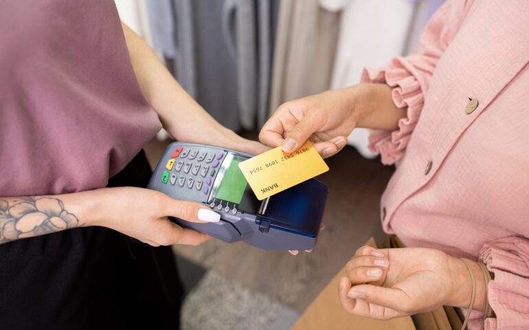 Close-up of young woman paying with credit card for her purchases in the shop